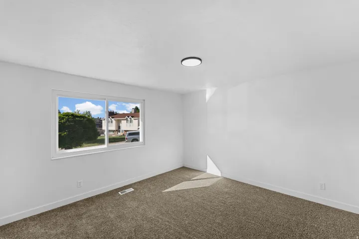 Wall-to-wall carpeting, white walls, and a white-framed window