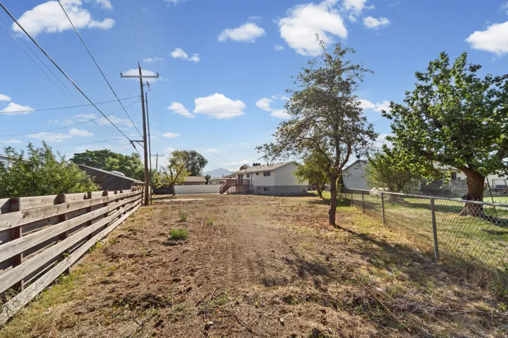 Expansive lot featuring a wood-panel fence, mature trees, and chain-link fencing