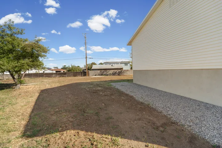 Exterior with horizontal siding over a stucco foundation, featuring a gravel perimeter and a tree