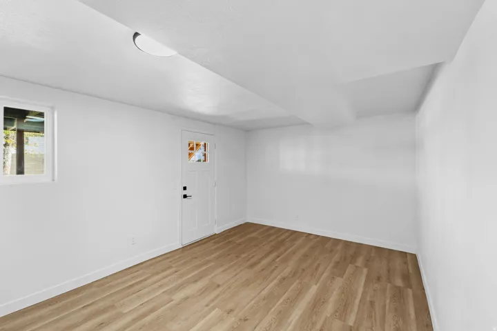 White painted walls, recessed ceiling lighting, wood-finish flooring, and a white door with decorative glass panels