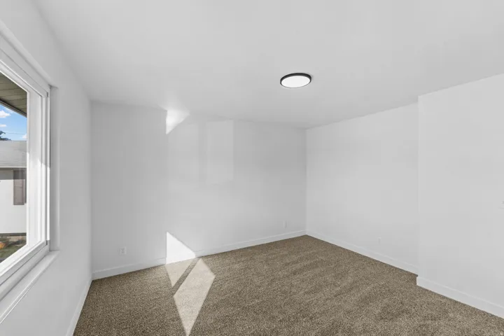 Neutral wall color, wall-to-wall carpeting, recessed ceiling light, white trim, and a window with white framing