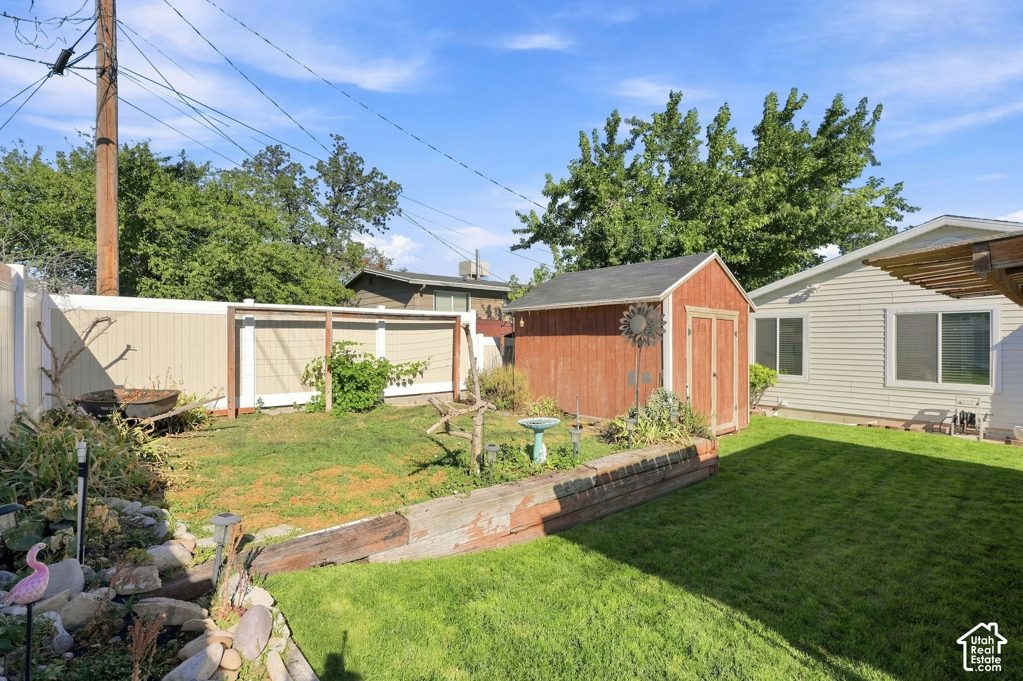 Expansive backyard featuring a manicured lawn, a red storage shed, and a privacy fence