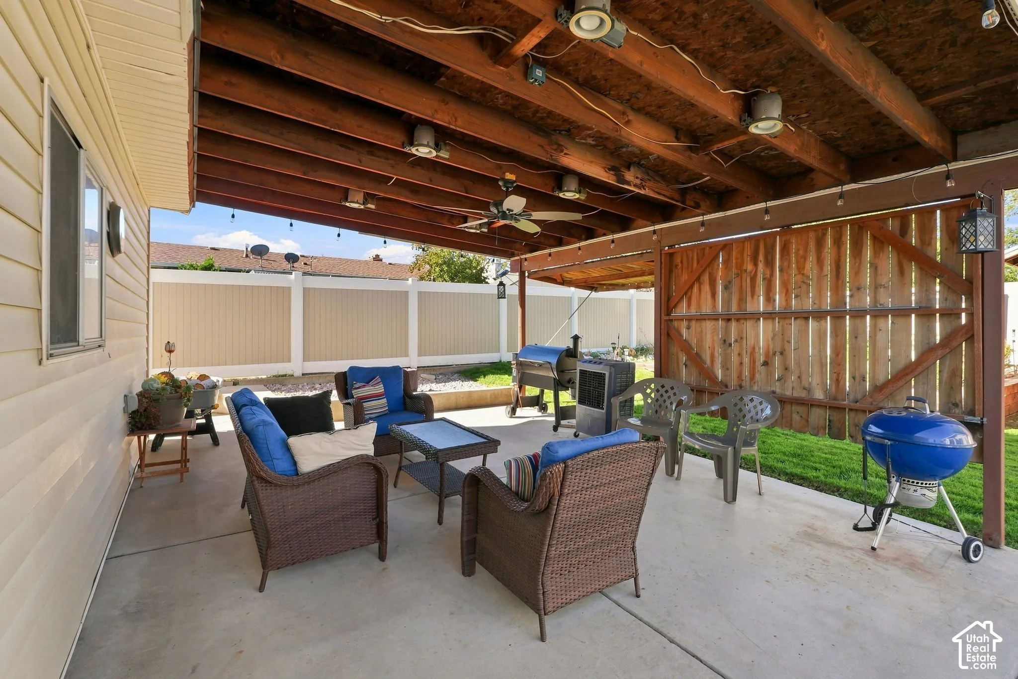 Expansive concrete patio with a wood-beamed overhead structure, recessed lighting, and a ceiling fan