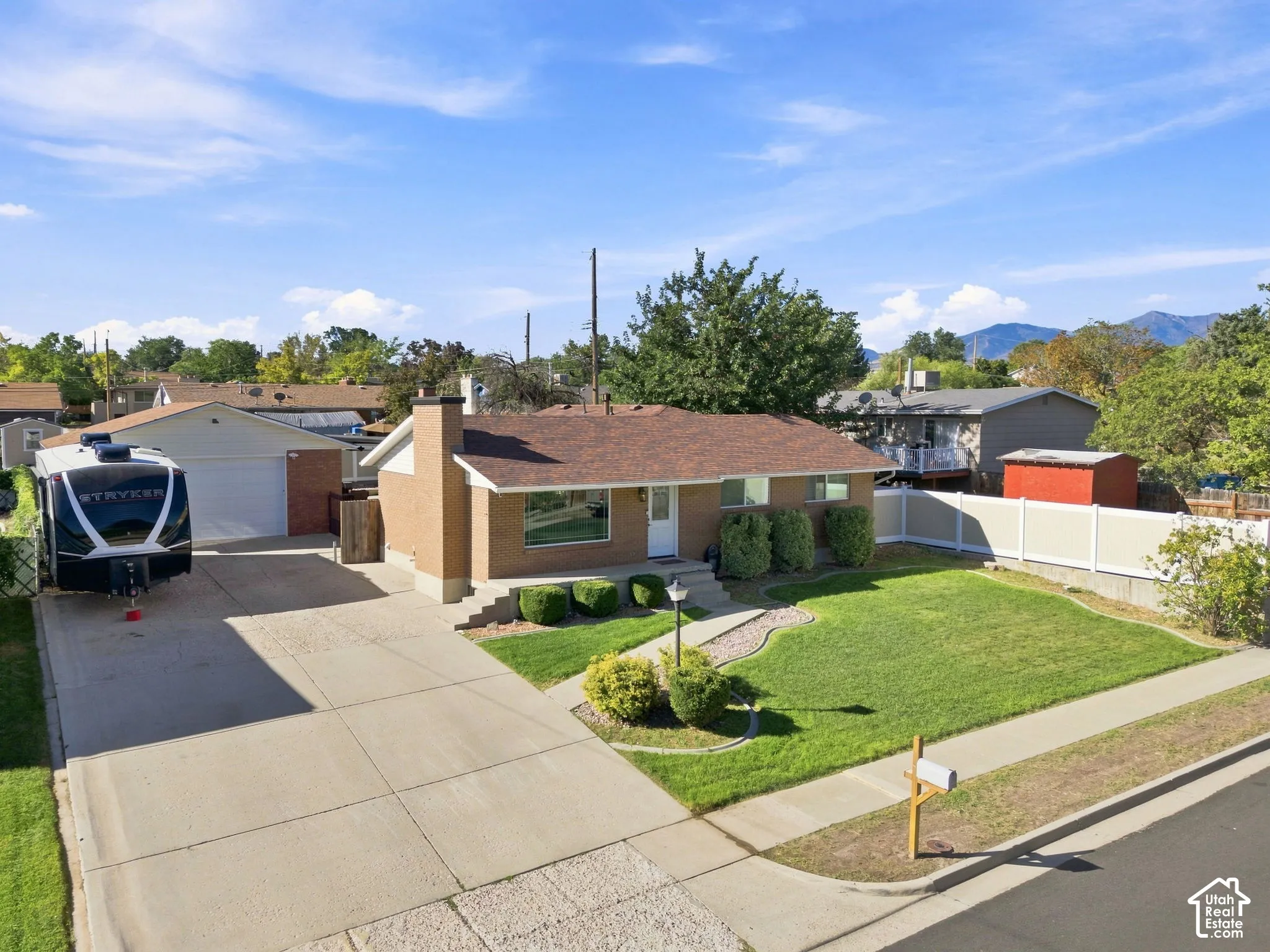 Brick exterior, attached garage, extended concrete driveway, established landscaping, and a fenced backyard