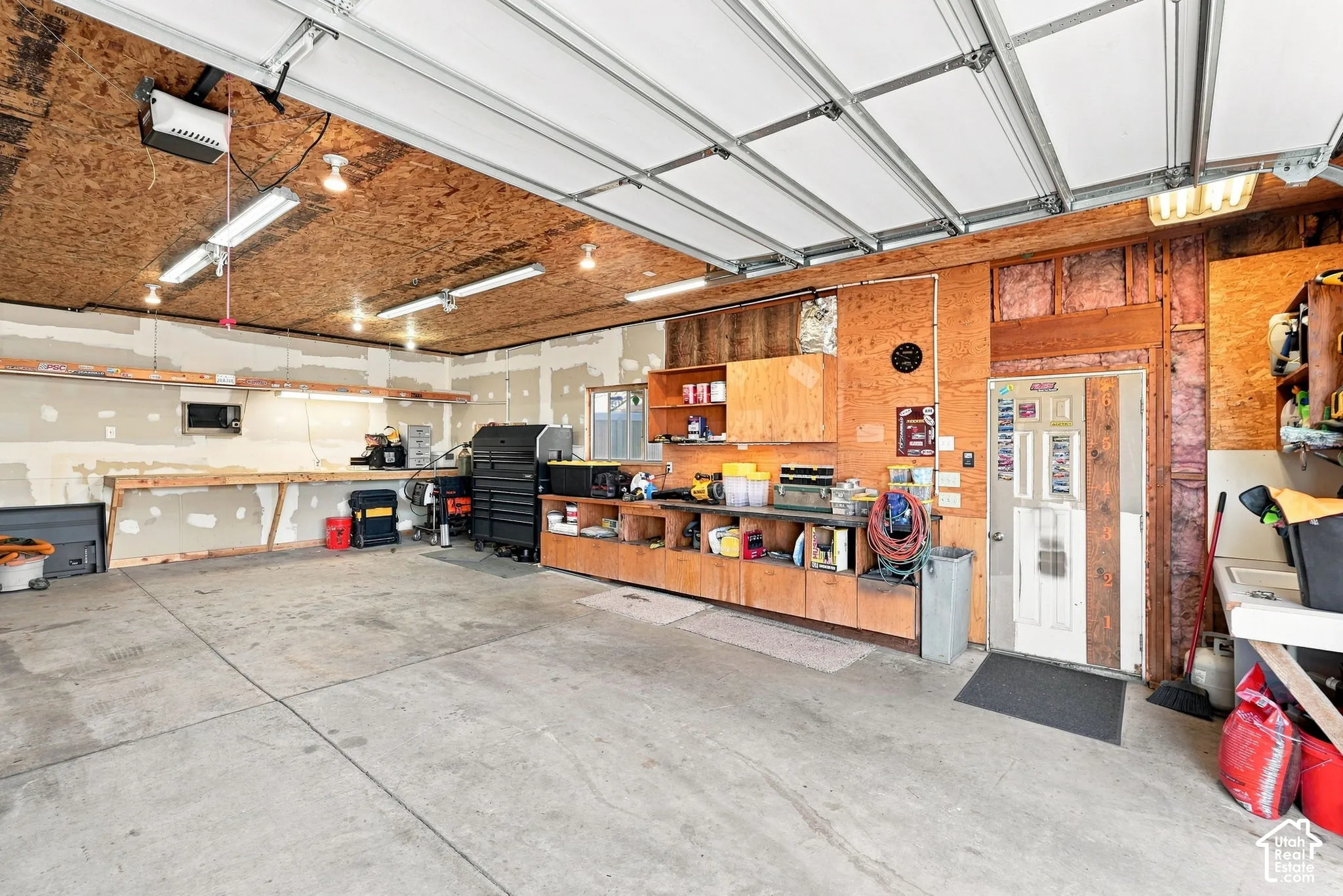 Concrete flooring, wood-paneled walls, built-in shelving, workbenches, overhead lighting, and heating and cooling!