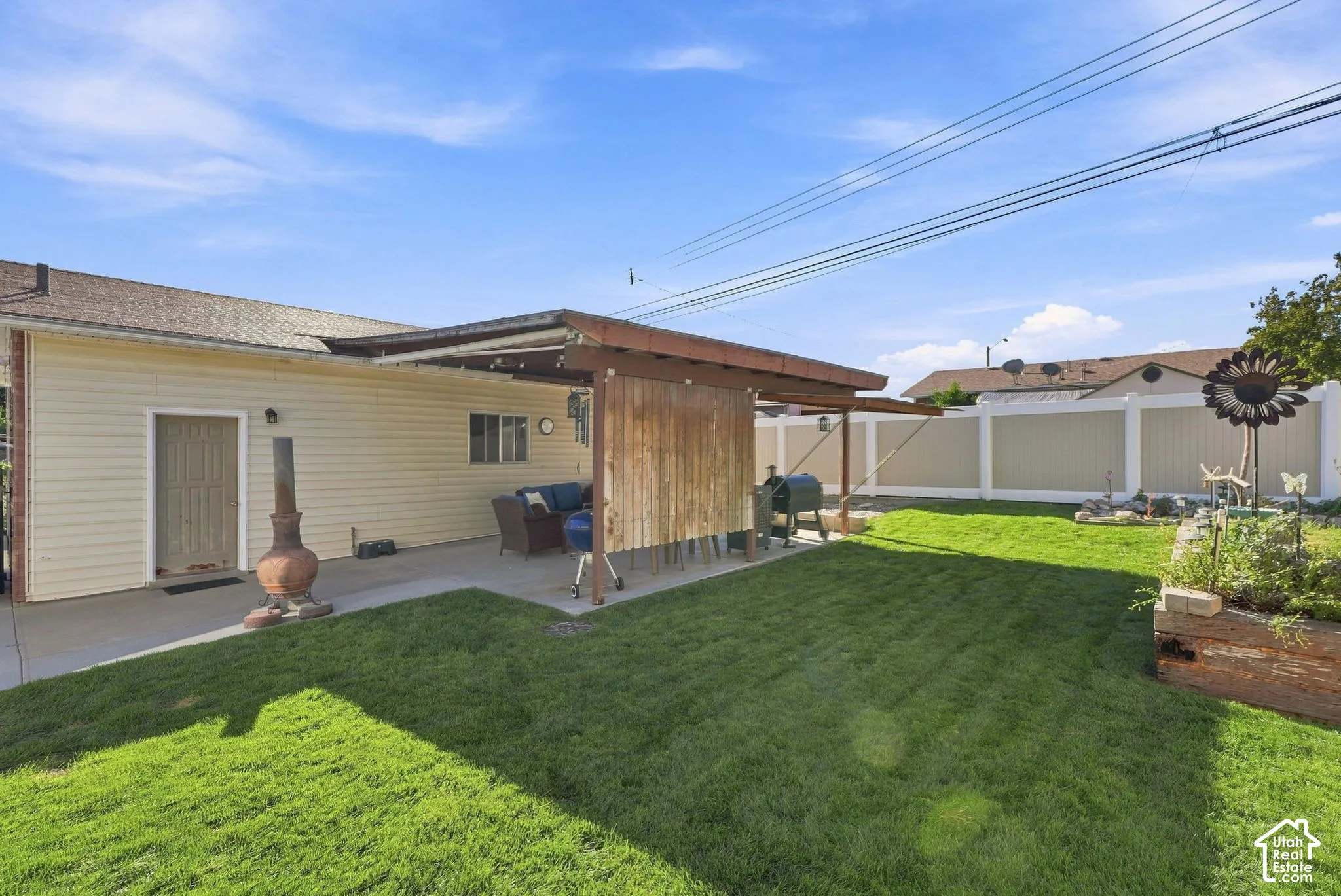 Expansive backyard featuring a manicured lawn, concrete patio, and a wood-frame patio cover