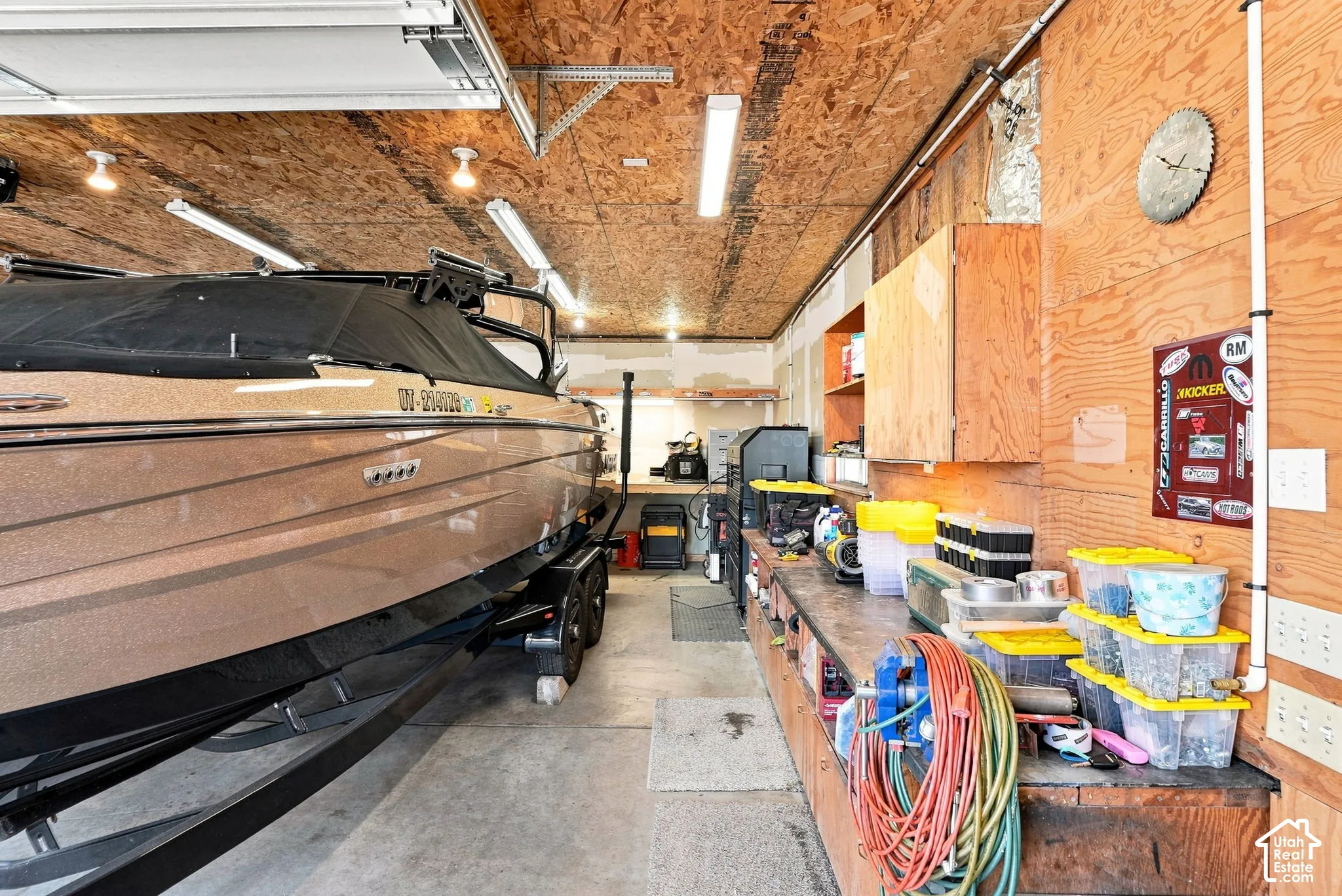 Detached garage featuring a concrete floor, plywood walls, built-in workbench, and overhead lighting, and heating and cooling!
