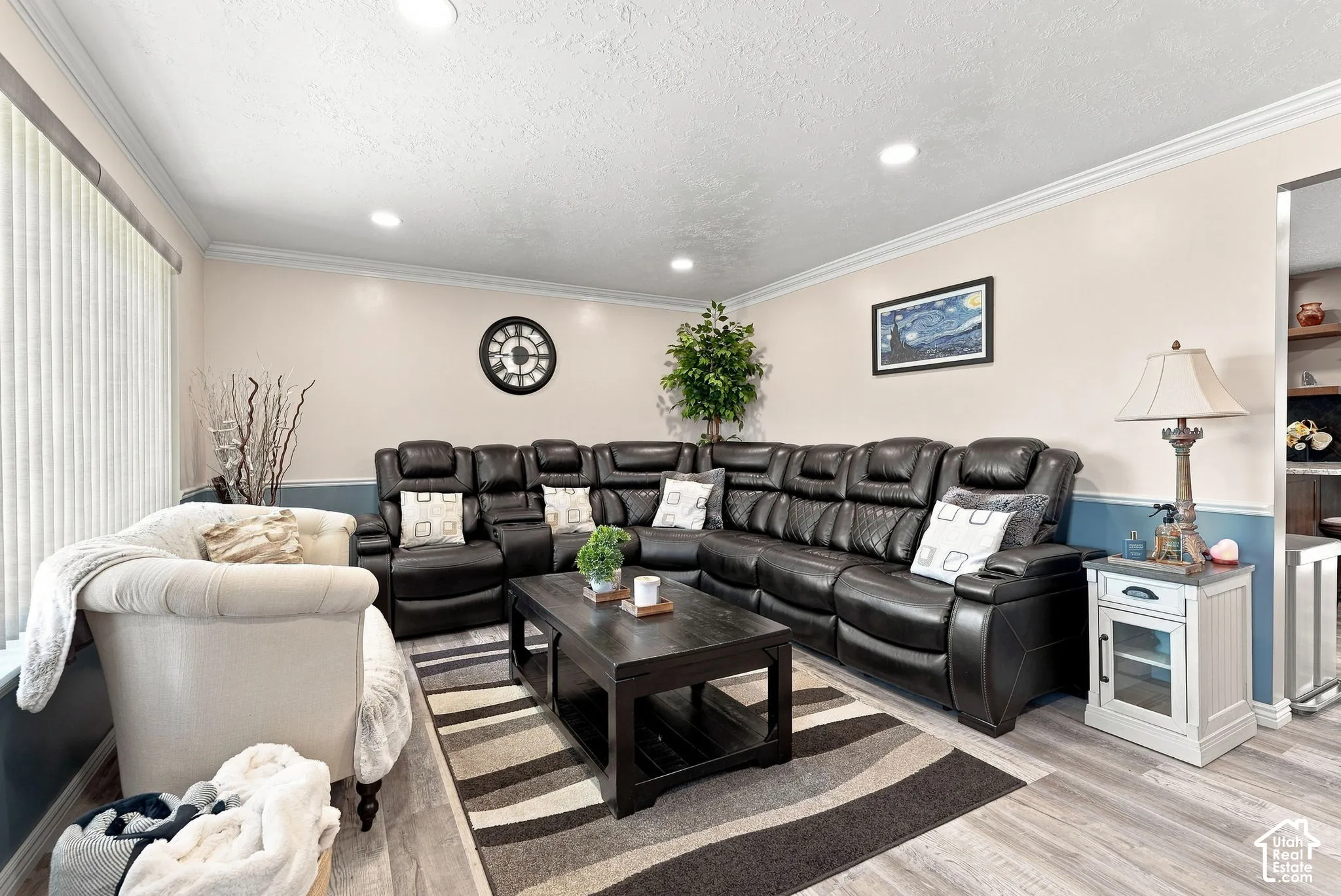Recessed ceiling lighting, crown molding, two-tone wall treatment, wood-finish flooring, and vertical window blinds