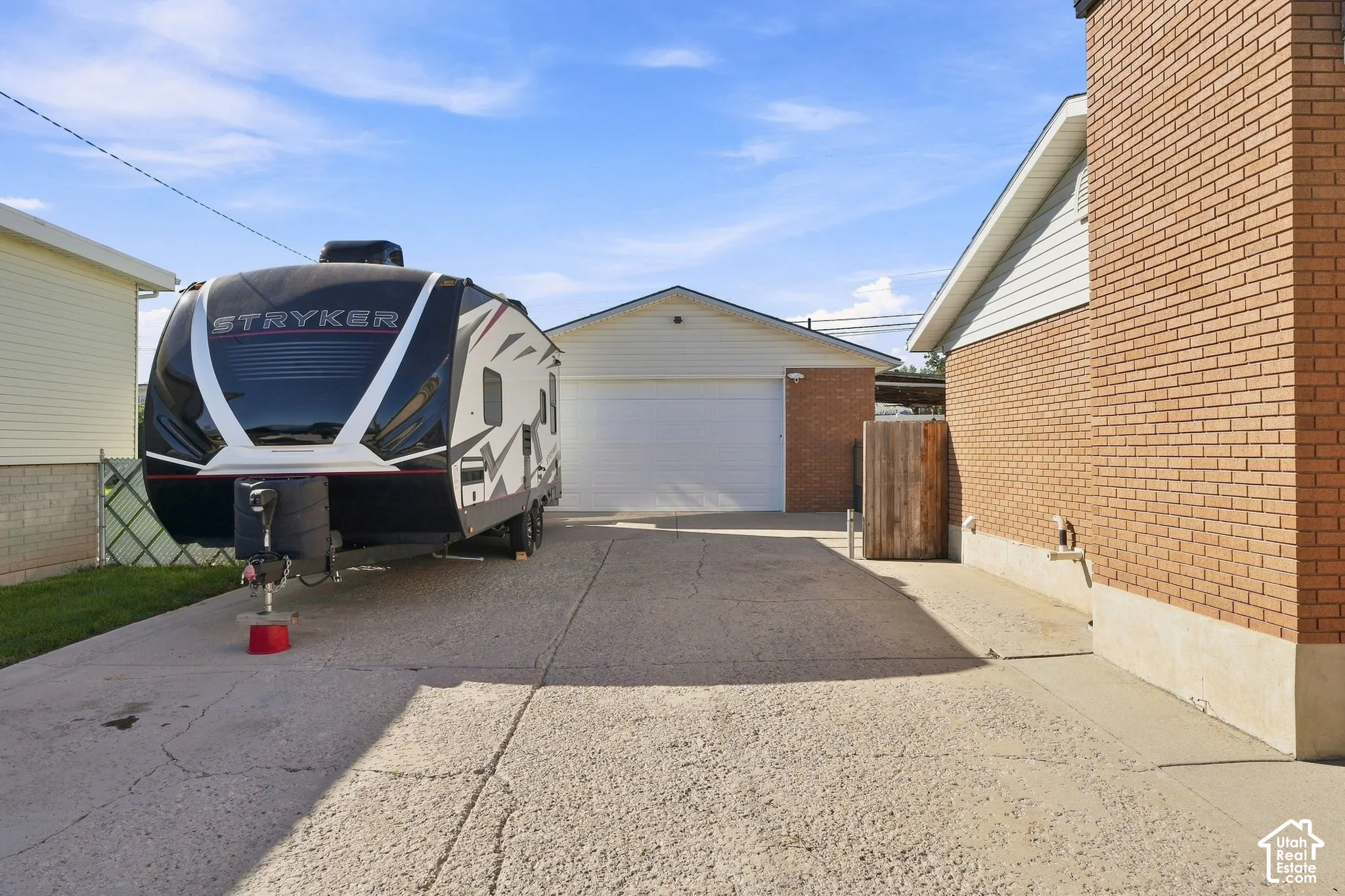 Detached garage with a 18x9 door, brick facade, and a long concrete driveway