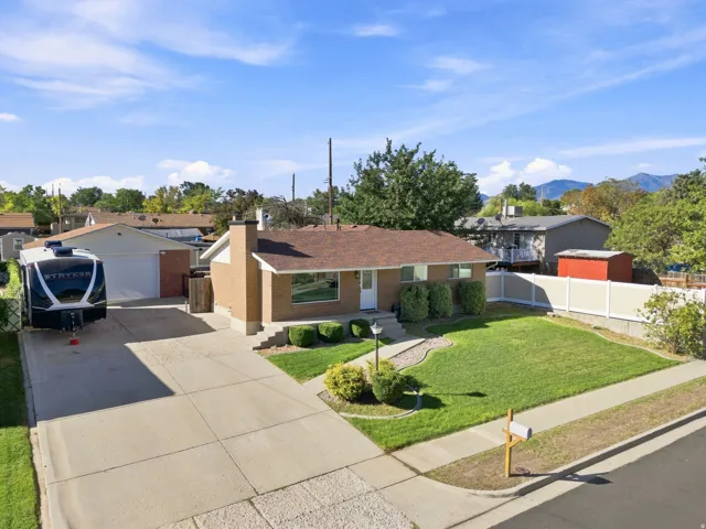 Brick exterior, attached garage, extended concrete driveway, established landscaping, and a fenced backyard