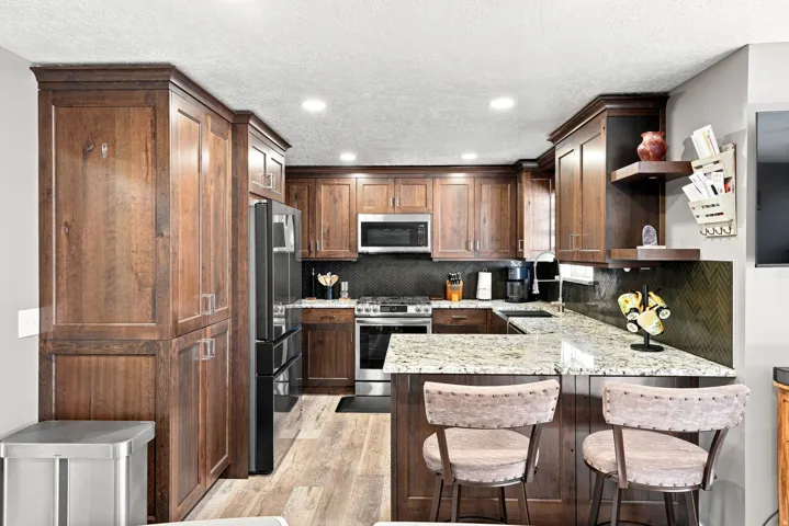 Custom cherrywood cabinetry, stainless steel appliances, granite countertops, tile backsplash, and recessed lighting