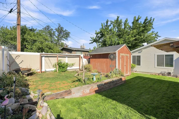 Expansive backyard featuring a manicured lawn, a red storage shed, and a privacy fence