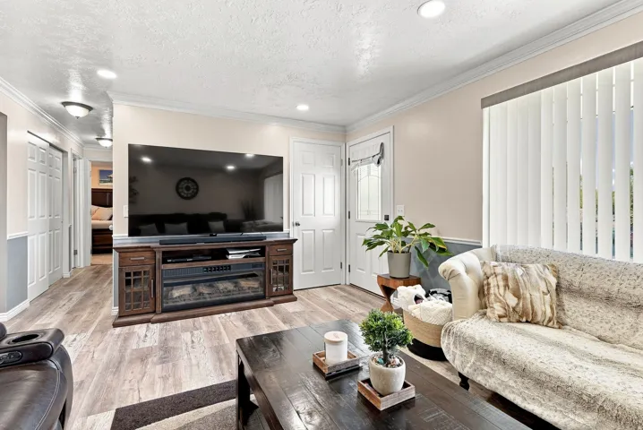Wood-finish flooring, recessed lighting, crown molding, chair rail molding, and a built-in media console with an integrated electric fireplace