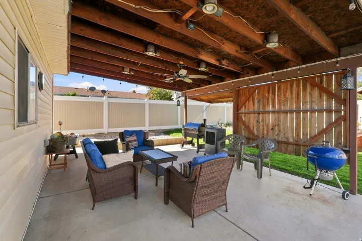 Expansive concrete patio with a wood-beamed overhead structure, recessed lighting, and a ceiling fan