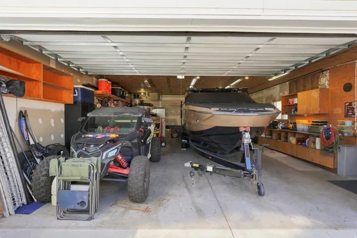 Spacious garage featuring concrete flooring, and built-in wood-finish shelving, and heating and cooling!