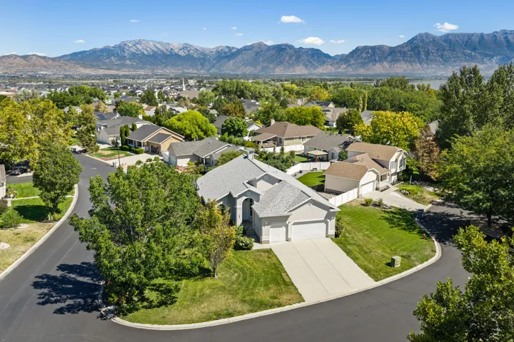 Exterior residence with a two-car garage, mature landscaping, and a paved driveway