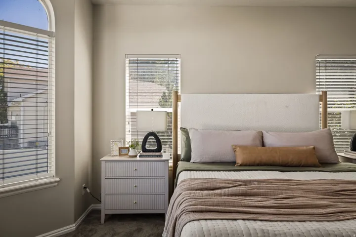 Arched window with blinds, carpeted flooring, and a window with blinds