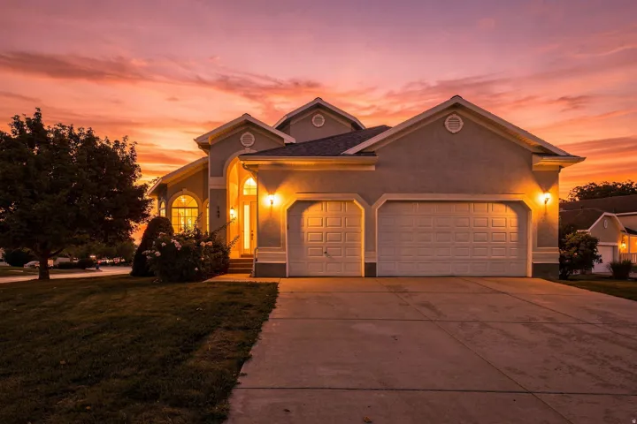 Stucco exterior with arched entry, two-car garage, and established landscaping