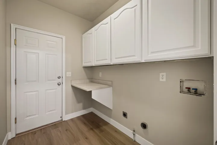 Room featuring wood-finish flooring, white paneled door, built-in upper cabinetry, and a floating countertop