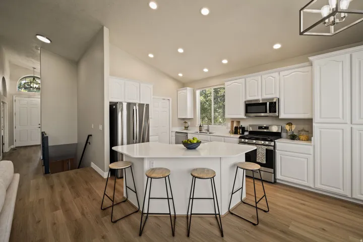 Kitchen featuring white cabinetry, stainless steel appliances, a center island with seating, wood-finish flooring, and recessed lighting