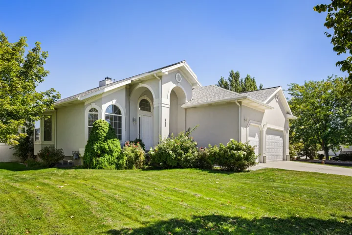 Stucco exterior featuring arched windows, an arched entry, a two-car garage, and a concrete driveway