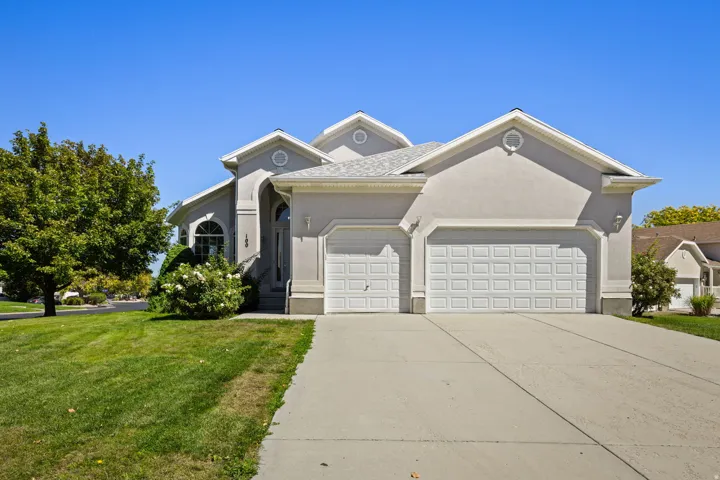 Stucco exterior, gabled roofline, arched entry, mature landscaping, and a two-car garage