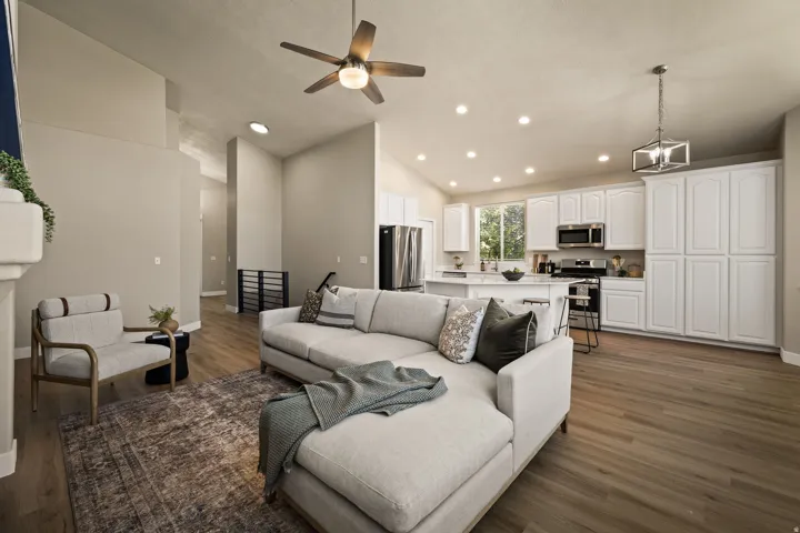 Vaulted ceilings, wood-finish flooring, recessed lighting, white cabinetry, and stainless steel appliances