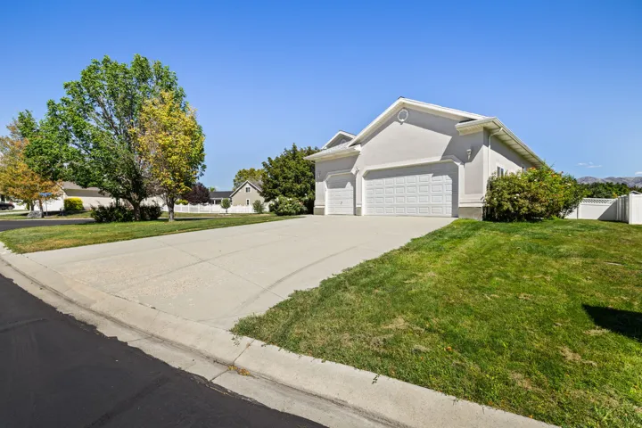 Stucco exterior with a pitched roof, two-car garage with panel doors, and a concrete driveway