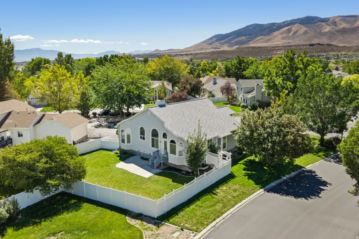 Contemporary residence with a light gray exterior, a white picket fence, and a lush green lawn