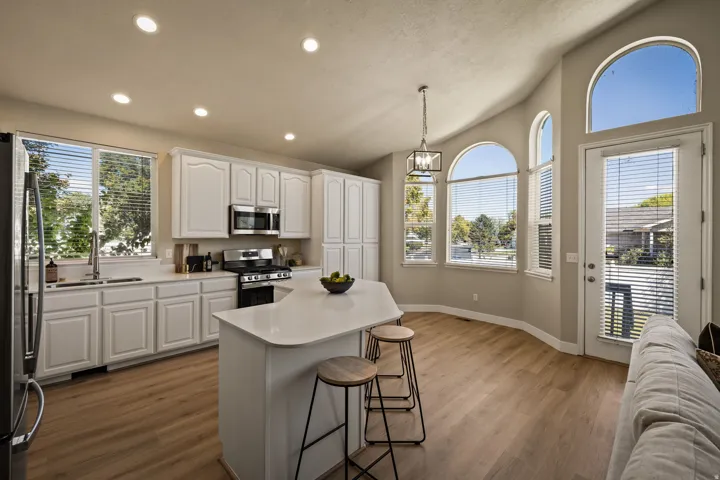 Kitchen featuring white cabinetry, stainless steel appliances, a center island with countertop seating, and wood-finish flooring