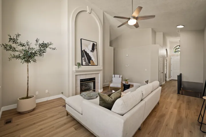 Vaulted ceilings, wood-finish flooring, built-in fireplace with arched surround, ceiling fan, and recessed lighting