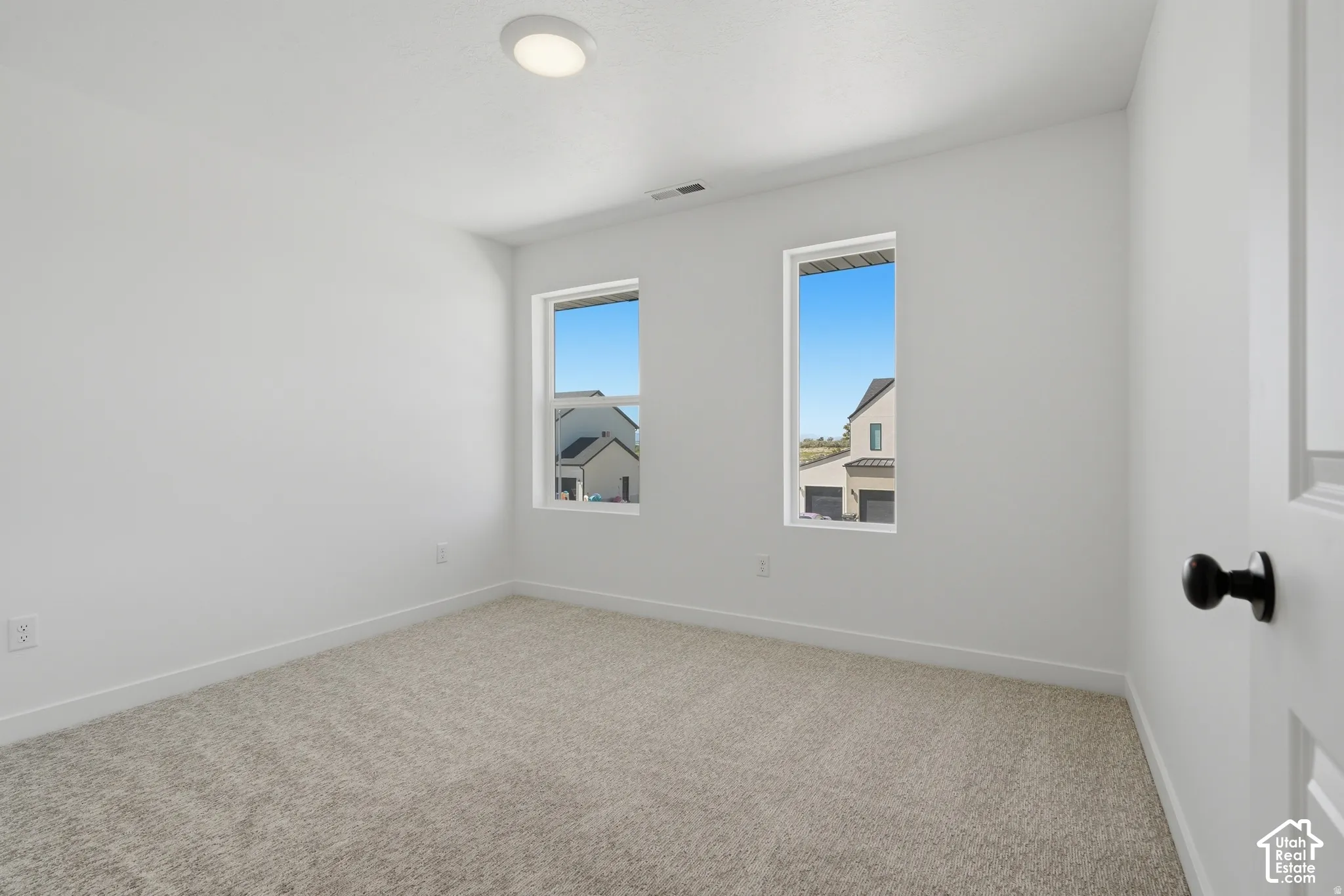 Neutral color palette with carpet flooring, bright white walls, and a contemporary ceiling light fixture