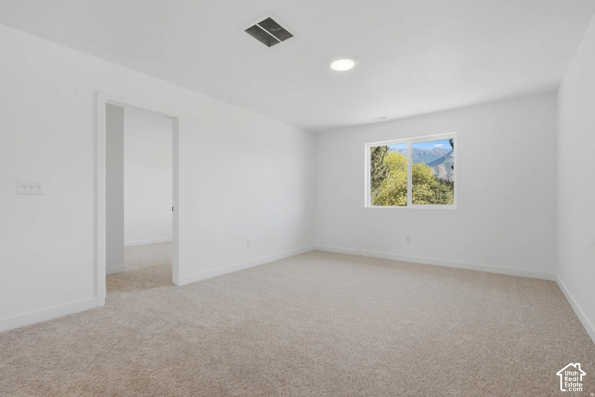 Expansive room featuring light-colored carpeting, white wall finishes, a single window, and recessed ceiling lighting