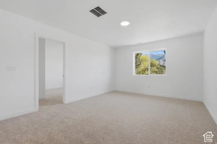 Expansive room featuring light-colored carpeting, white wall finishes, a single window, and recessed ceiling lighting