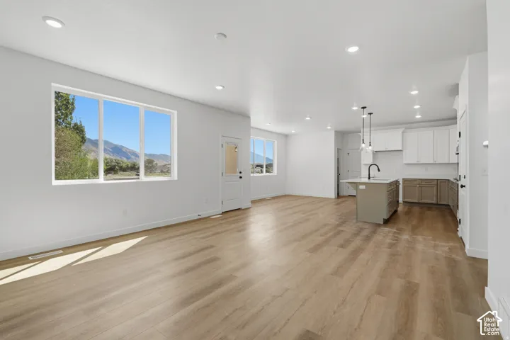 Open-concept living area featuring wood-finish flooring, recessed lighting, and a kitchen island with pendant lighting
