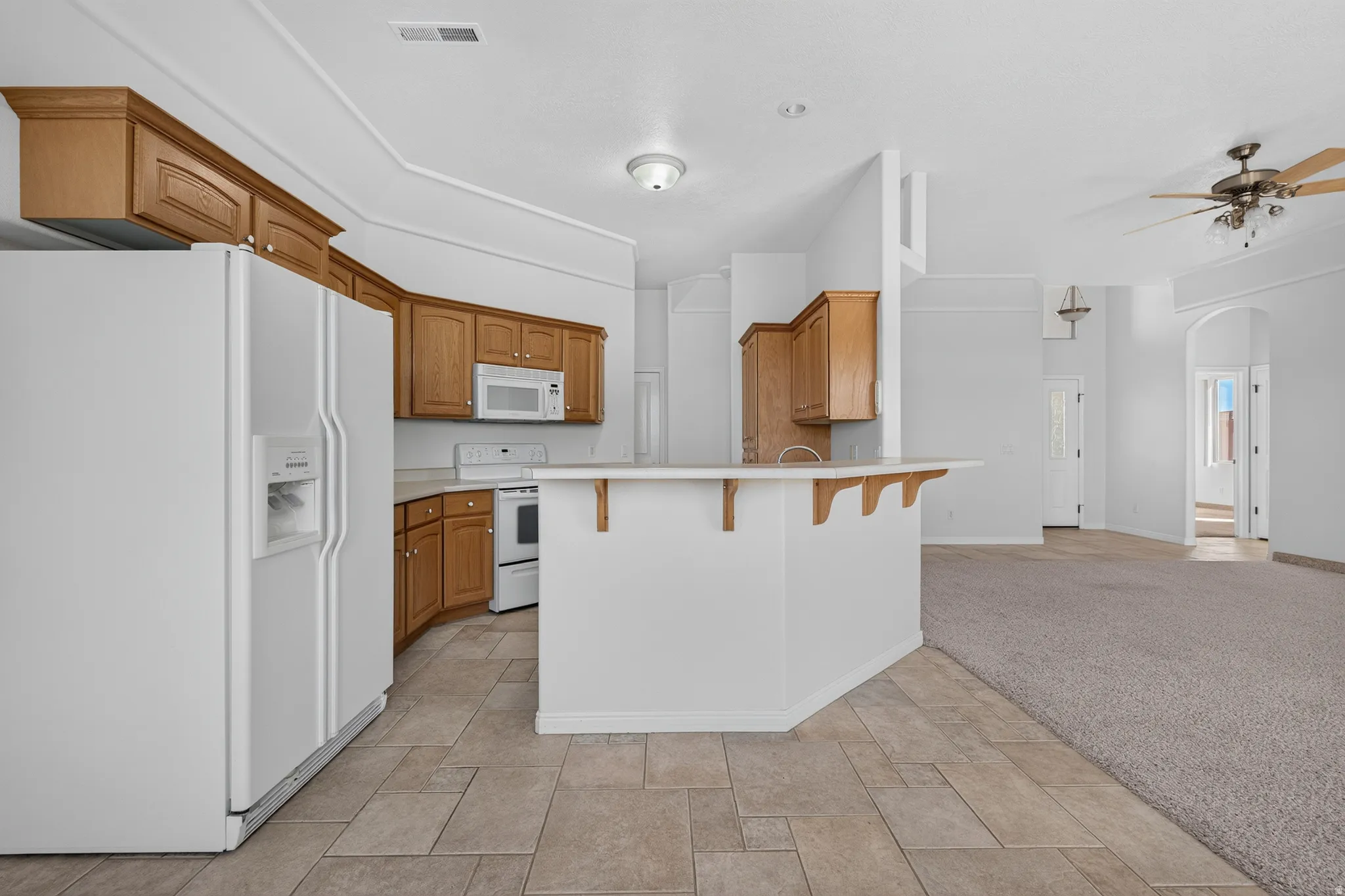 Kitchen featuring wood cabinetry, white appliances, and tiled flooring