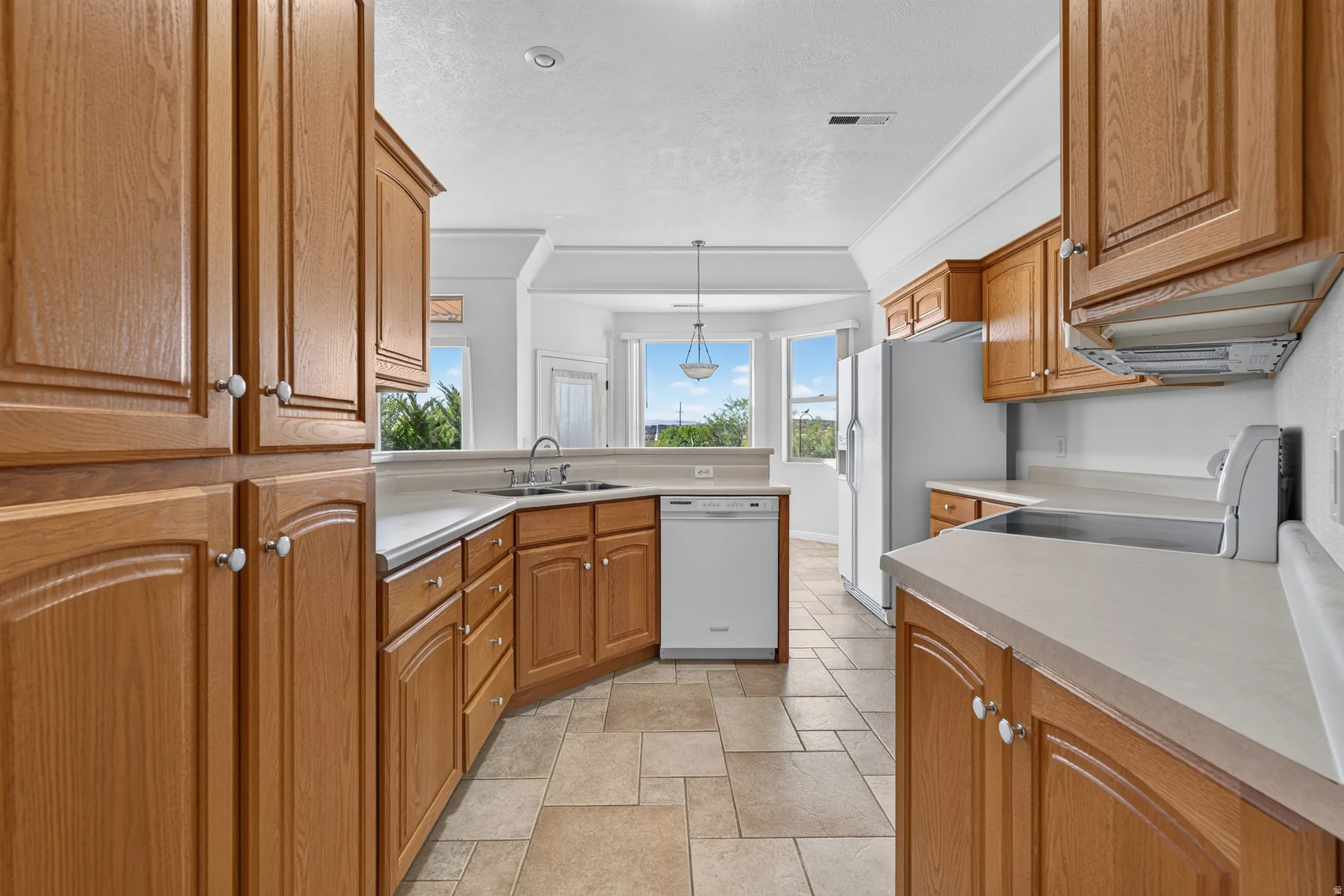 Kitchen featuring abundant wood cabinetry, light-toned countertops, integrated appliances, and tiled flooring