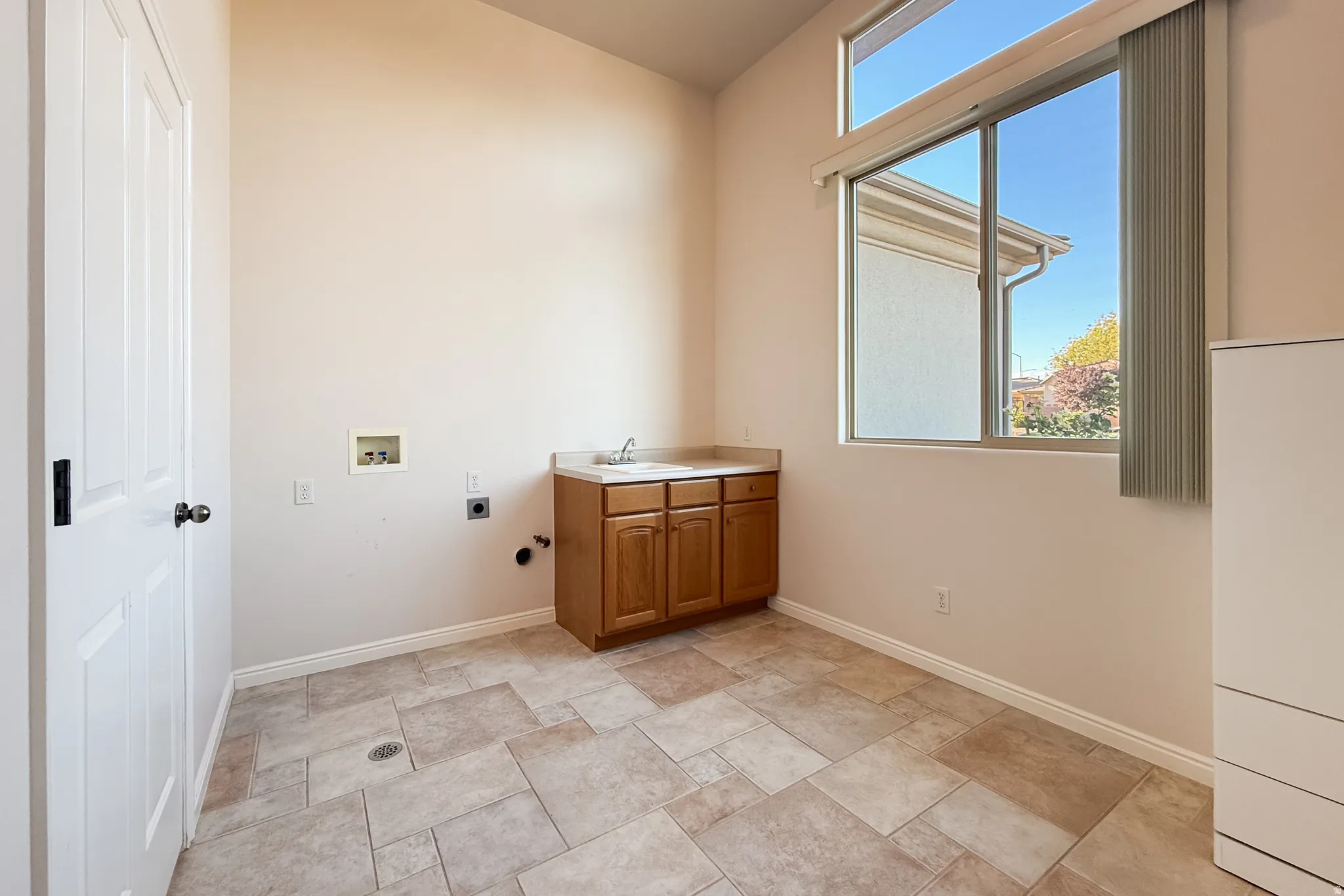 Vaulted ceiling, large window, wood-finish cabinetry, countertop, and tile flooring