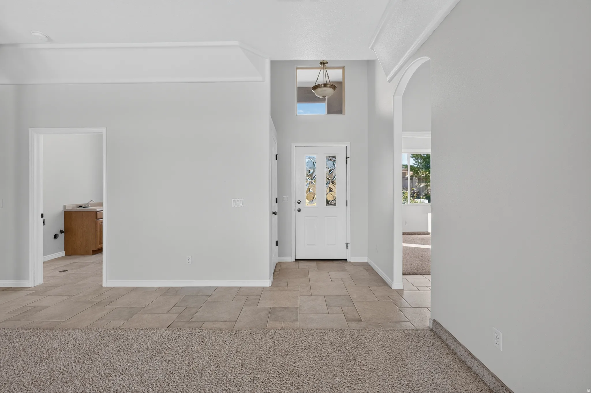 Foyer with decorative glass panel door, transom window, and integrated overhead lighting