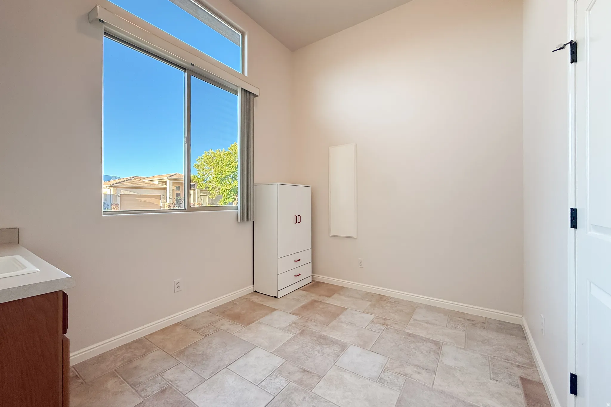 Large window with transom, tile flooring, built-in cabinetry, and integrated sink with countertop