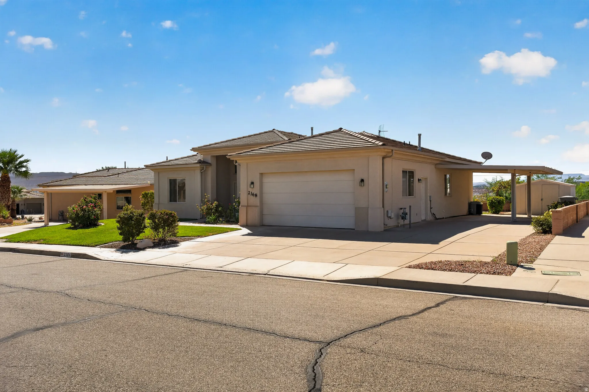 Stucco exterior with a tile roof, an attached two-car garage, a covered carport, and a concrete driveway