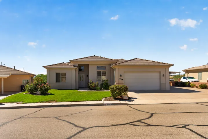 Stucco exterior with a two-car garage, concrete driveway, and front lawn