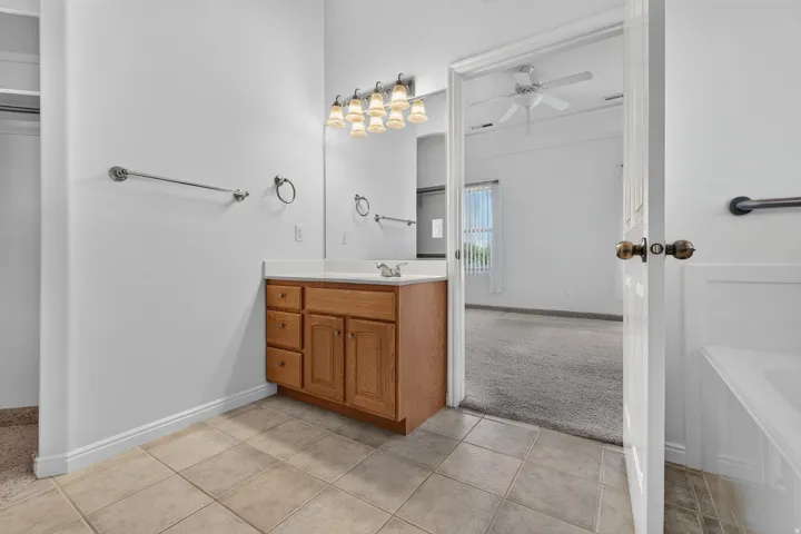 Bathroom vanity with natural wood-finish cabinetry, integrated sink, and wall-mounted light fixture