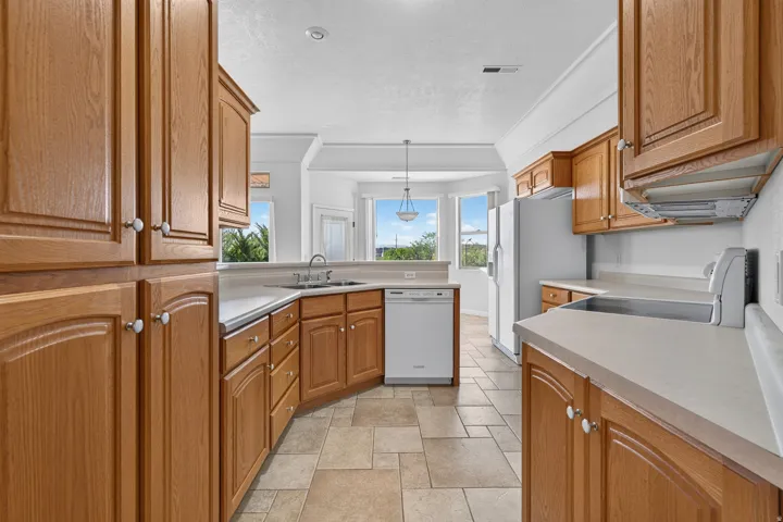 Kitchen featuring abundant wood cabinetry, light-toned countertops, integrated appliances, and tiled flooring