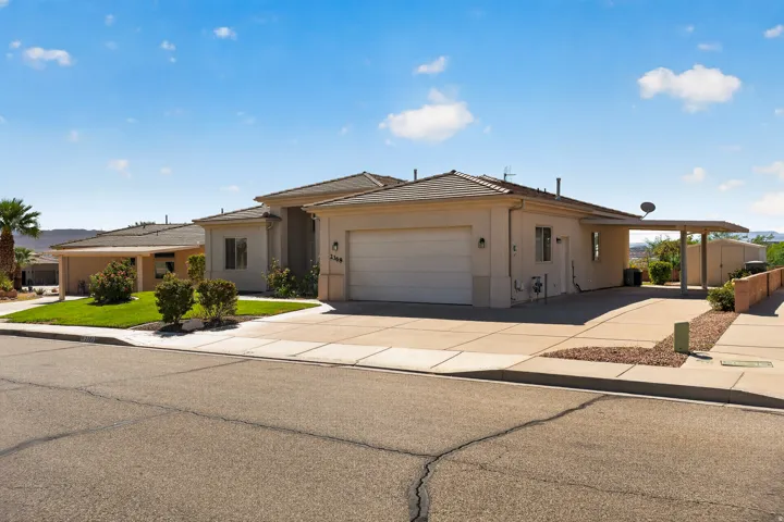 Stucco exterior with a tile roof, an attached two-car garage, a covered carport, and a concrete driveway
