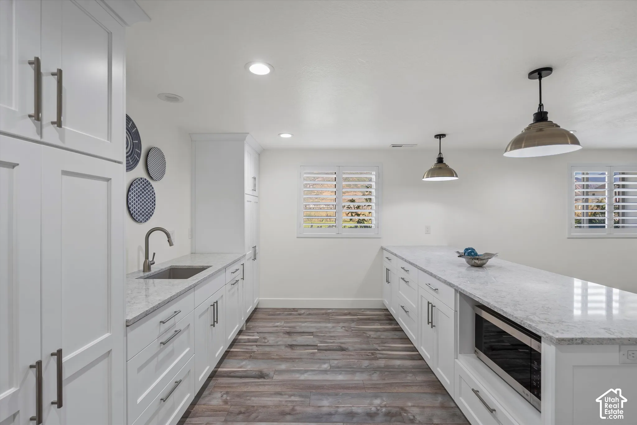 White shaker cabinetry, wood-finish flooring, undermount sink, recessed lighting, and a built-in microwave
