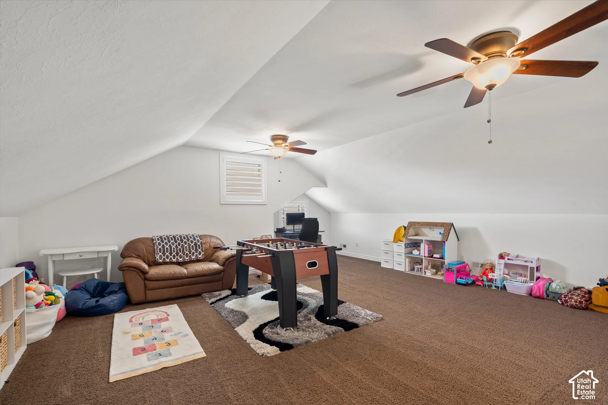 Sloped ceilings with recessed lighting, brown carpeted flooring, and two ceiling fans with integrated lighting