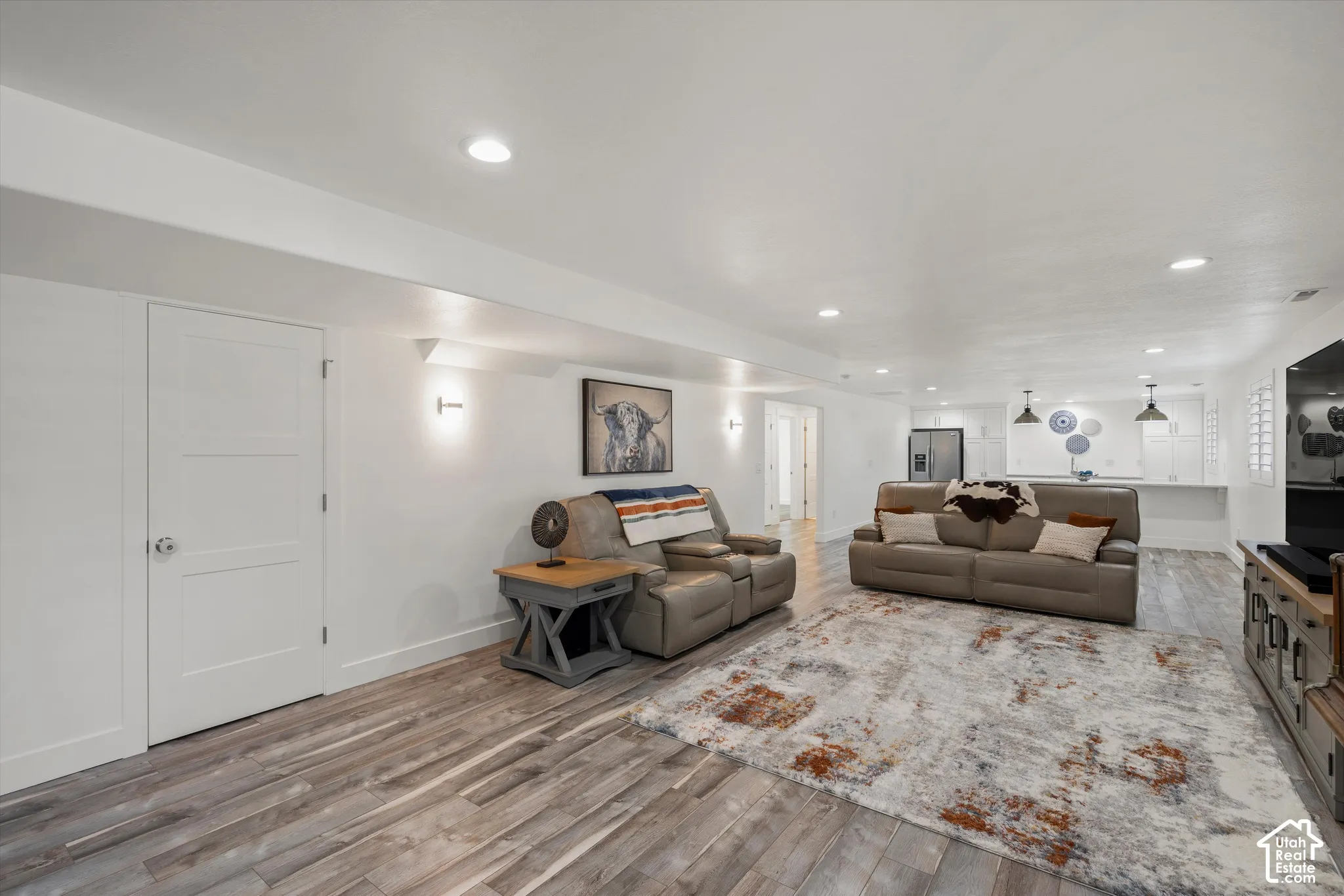 Open-concept living area with wood-finish flooring, recessed lighting, and wall sconces