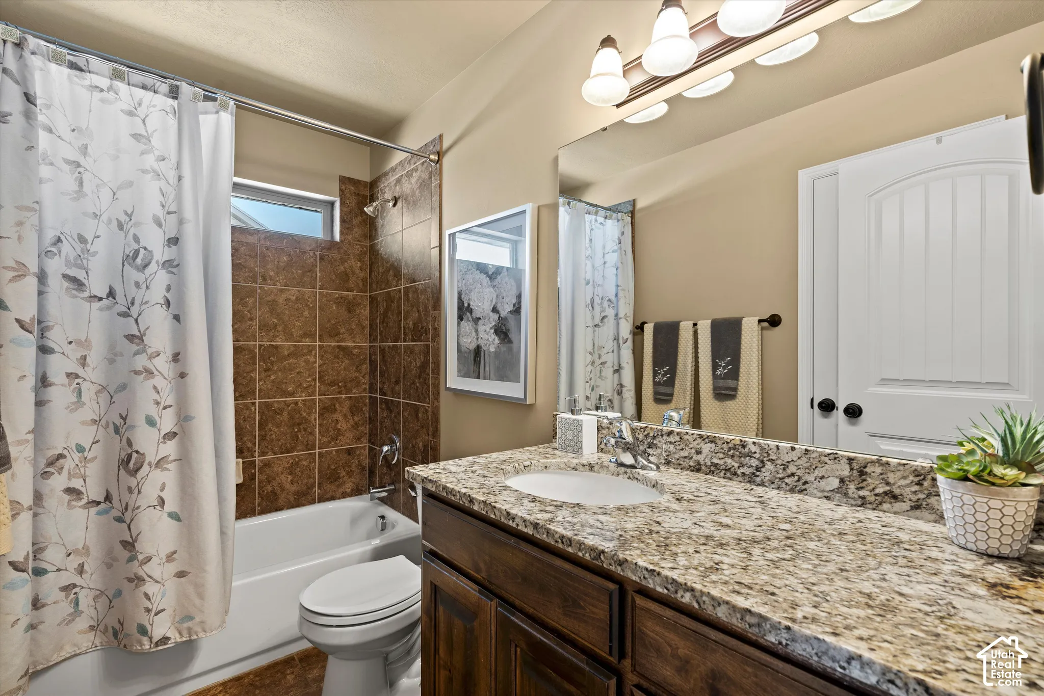 Bathroom featuring a built-in vanity with a granite-style countertop, undermount sink, and a large mirror