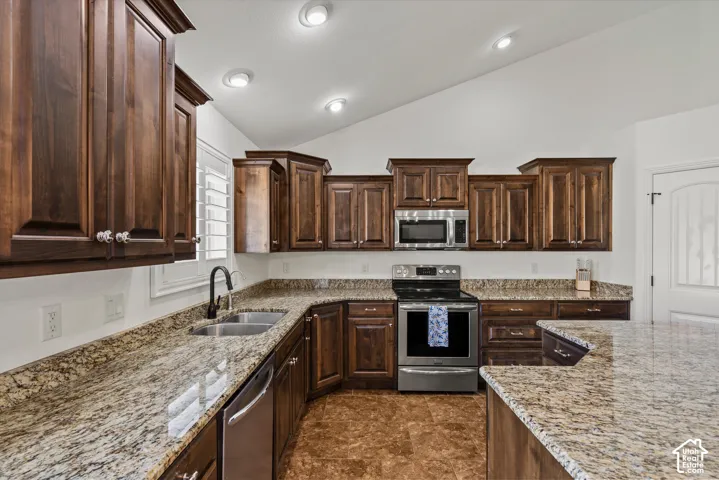 Kitchen featuring rich wood cabinetry, stainless steel appliances, granite countertops, and recessed lighting